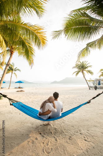 a couple loving hug each other while seating on a hammock at the beach