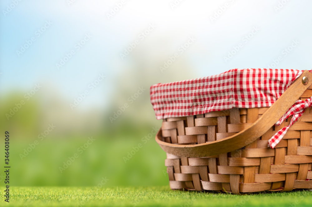 Obraz premium On green grass, a picnic basket against the backdrop of the landscape. A backdrop for relaxing and spending the weekend. Picnic and relaxation