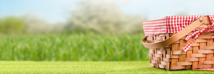 On green grass, a picnic basket against the backdrop of the landscape. A backdrop for relaxing and spending the weekend. Picnic and relaxation