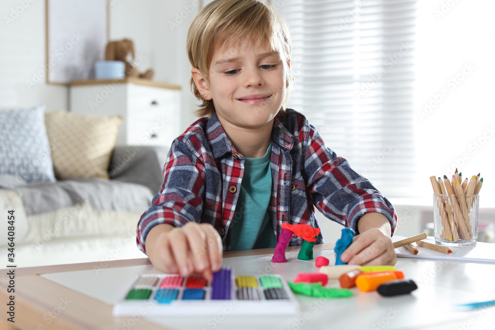 Little boy playing with plasticine at table indoors. Creative hobby Little boy playing with plasticine at table indoors. Creative hobby