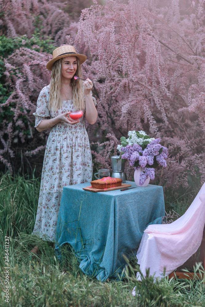 Fototapeta premium Beautiful young girl in pink has breakfast on a background of rosewood.