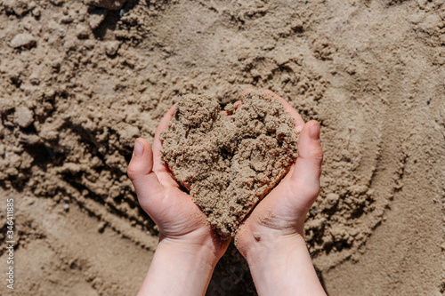 baby hands holding heart shaped sand