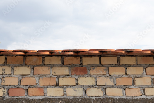 brick fence with tiles and cloudy sky