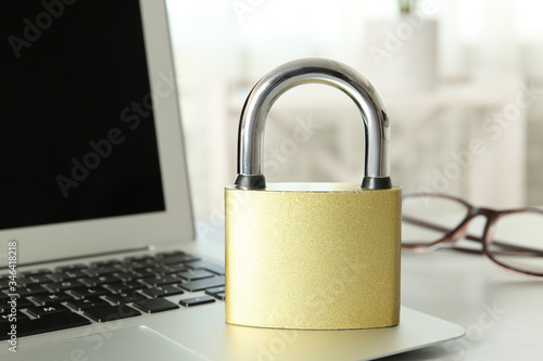 Metal lock and laptop on table, closeup. Protection from cyber attack