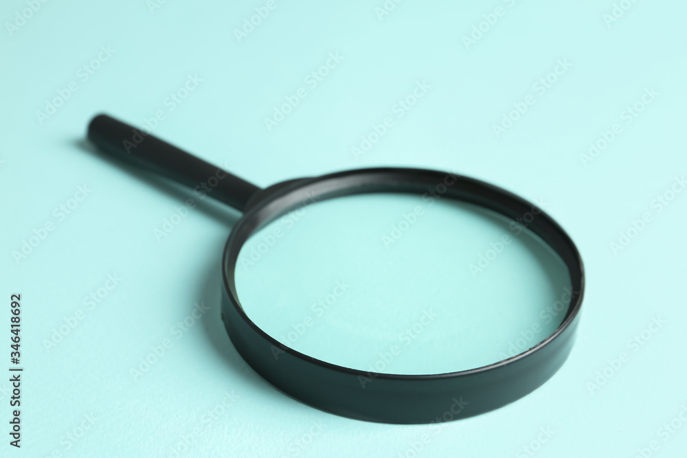 Magnifying glass on light blue background, closeup. Search concept Magnifying glass on light blue background, closeup. Search concept
