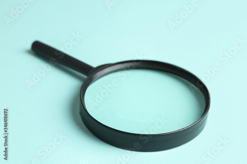 Magnifying glass on light blue background, closeup. Search concept