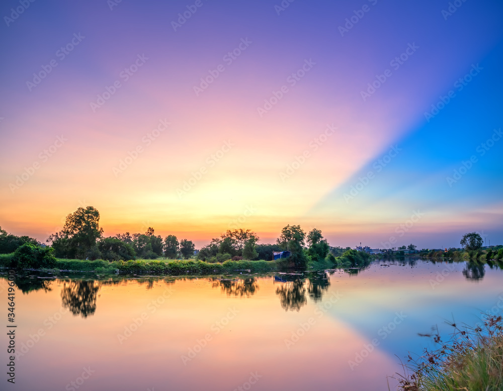 The sun rays on the horizon dramatically through clouds, Magic purple sunset by the river