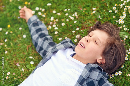 Portrait of young boy while lying in spring green garden