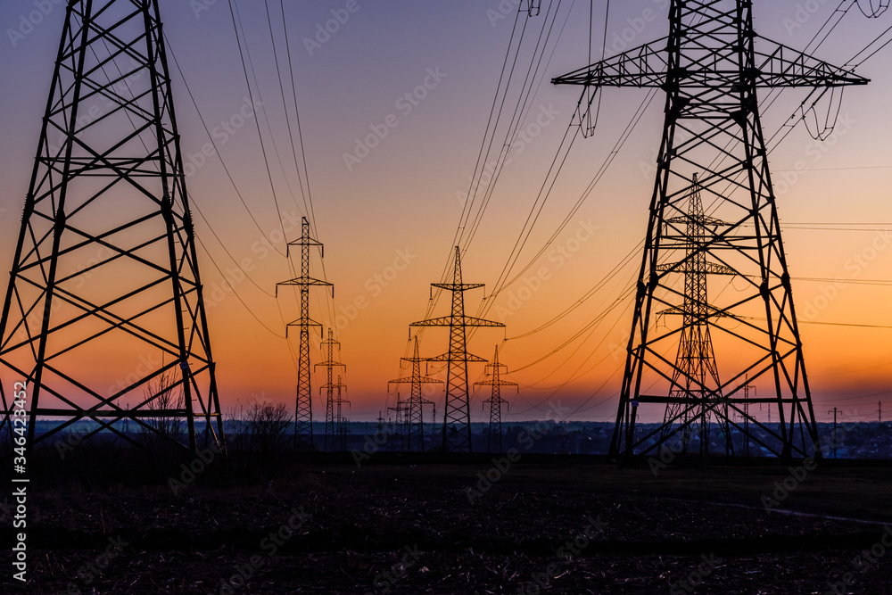 High voltage power line in a field at sunset