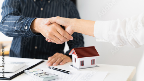 Real estate agent and Customer hand shaking with contract to buying a house.