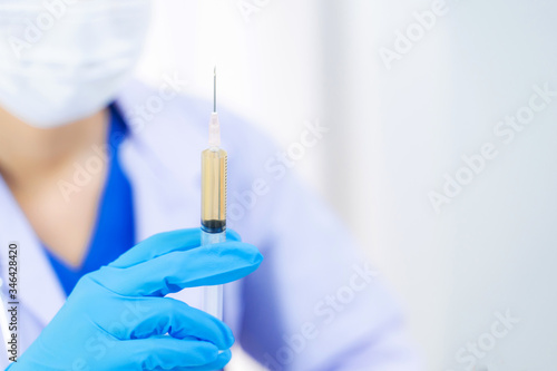 Doctor holding medical injection syringe in hospital.