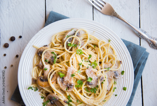 Fotografia Spaghetti pasta with mushrooms, creamy sause and parsley on white