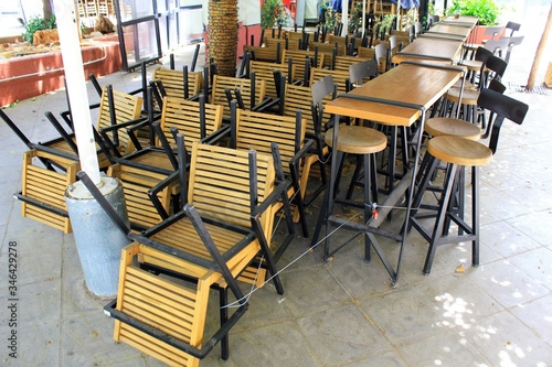 Athens, Greece, May 6 2020 - Tables and chairs stacked outside closed cafe-restaurant during the Coronavirus lockdown.