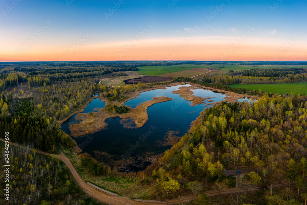 Aerial view of a pond surrounded by forest at sunset