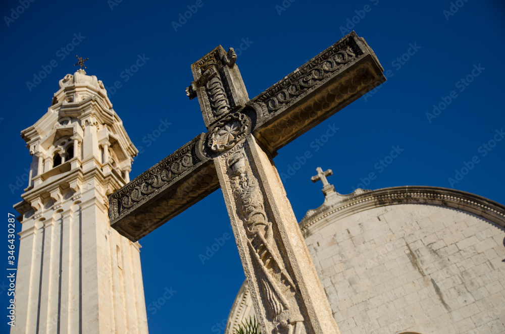 Croatian seaside town, Dalmatia, medieval Roman Catholic church tower with cross, blue sky, sunny summer. Croatian seaside town, Dalmatia, medieval Roman Catholic church tower with cross, blue sky, sunny summer.