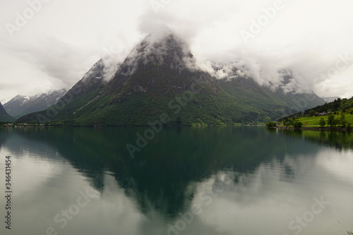 Reflections of misty mountains in the waters of Oppstrynsvatn lake in Norway 