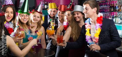 Portrait of women and men in caps with cocktails