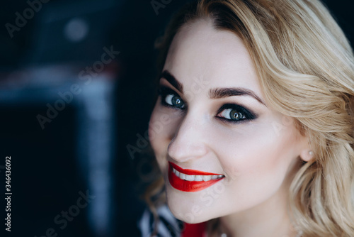 Closeup portrait of a beautiful blonde woman with bright makeup red lips and smoky eyes. Soft selective focus. Toned photo.