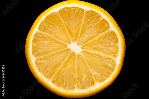 Half a ripe lemon close-up on a black background
