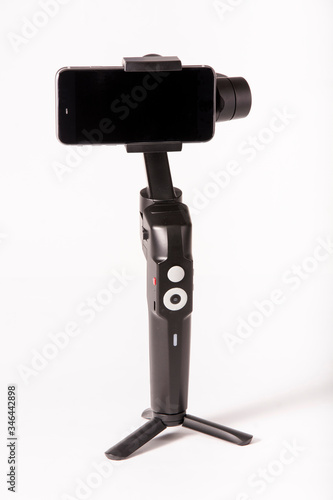Fotograf mit Video-Gimbal, Smartphone-Stabilisator und Stativ für ausgeglichene Aufnahmen im Studio auf weißem Hintergrund.