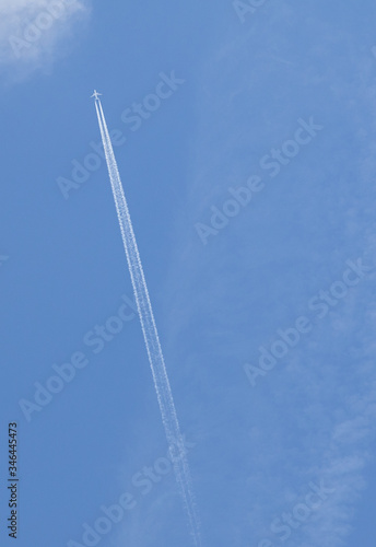 Blue sky with clouds and a airplane with white smoke behind