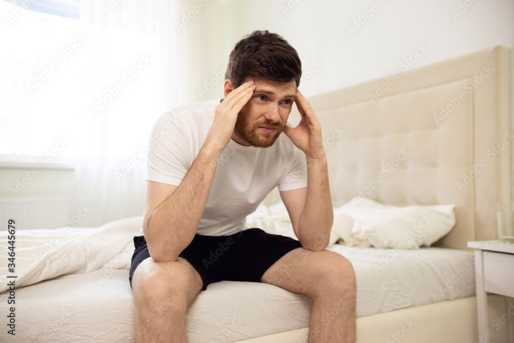 Hangover. Man Sitting on Bed Holding Head. Man in Bed Morning Headache. Glass of Water Hangover. Man Sitting on Bed Holding Head. Man in Bed Morning Headache. Glass of Water