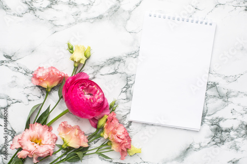 Notebook and pink flower bouquet on marble background