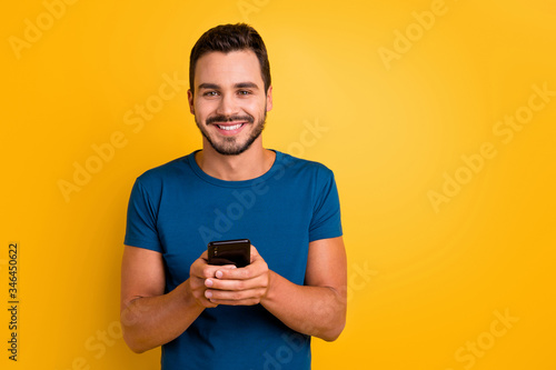 Close-up portrait of his he nice attractive glad cheerful cheery guy using cell comment feedback repost smm service isolated over bright vivid shine vibrant yellow color background © deagreez