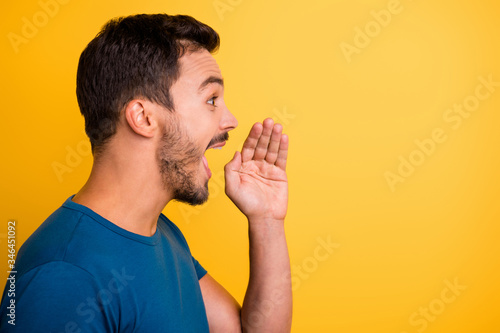 Close-up profile side view portrait of his he nice attractive glad positive cheerful cheery guy saying good news isolated over bright vivid shine vibrant yellow color background