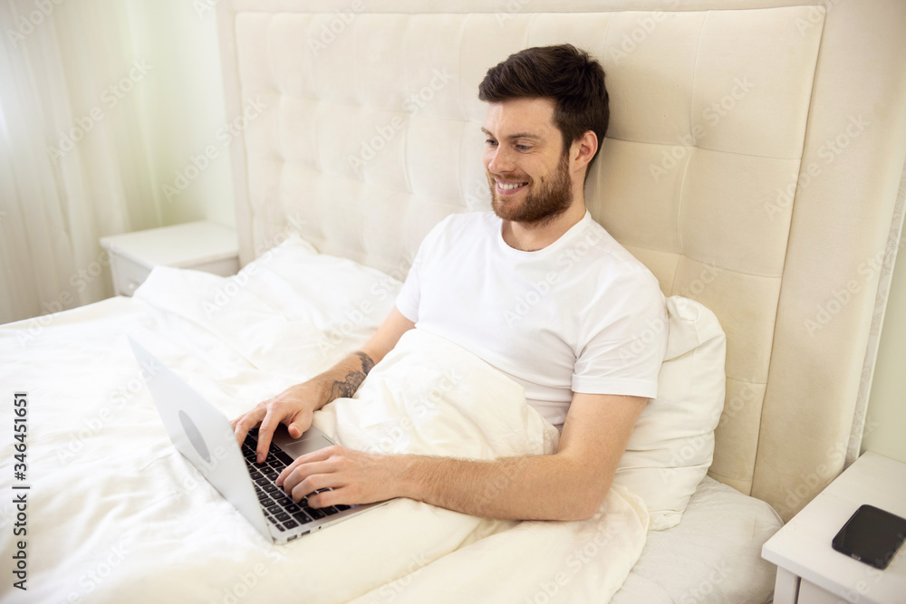 Man Working in Bed. Man Working at Home. Man Using Laptop in Bed. Quarantine, Home Work, Medical Care. Man Working in Bed. Man Working at Home. Man Using Laptop in Bed. Quarantine, Home Work, Medical Care.