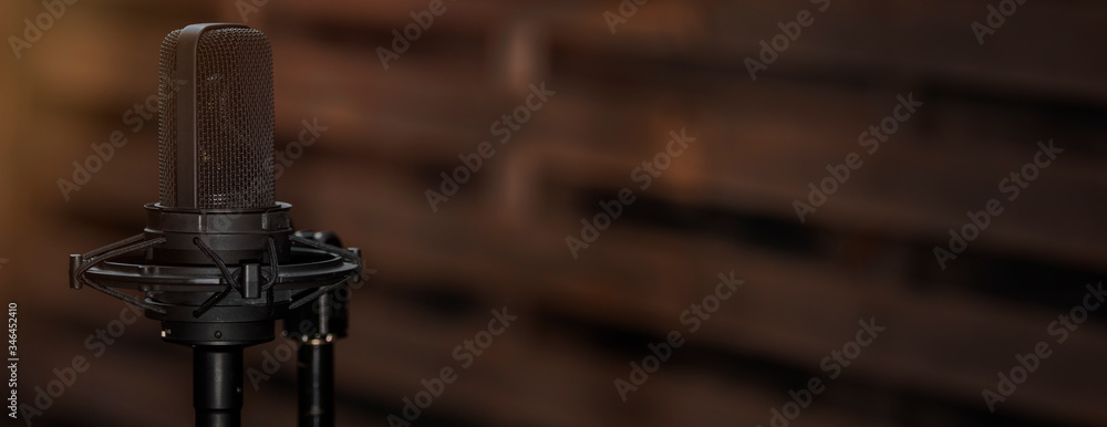 Professional microphone on dark brown wooden background. Music, voice or podcast recording large banner. Professional microphone on dark brown wooden background. Music, voice or podcast recording large banner.