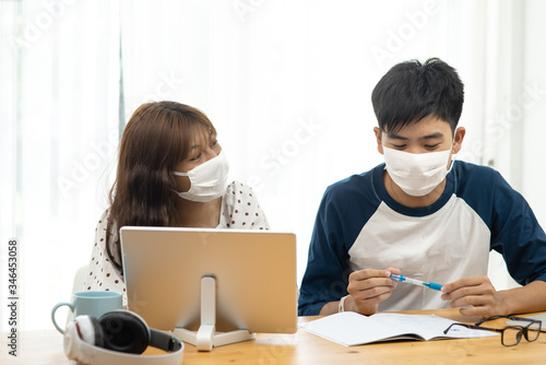 Asian teenager using  laptop and tablet for online schooling from home together, quarantine concept.