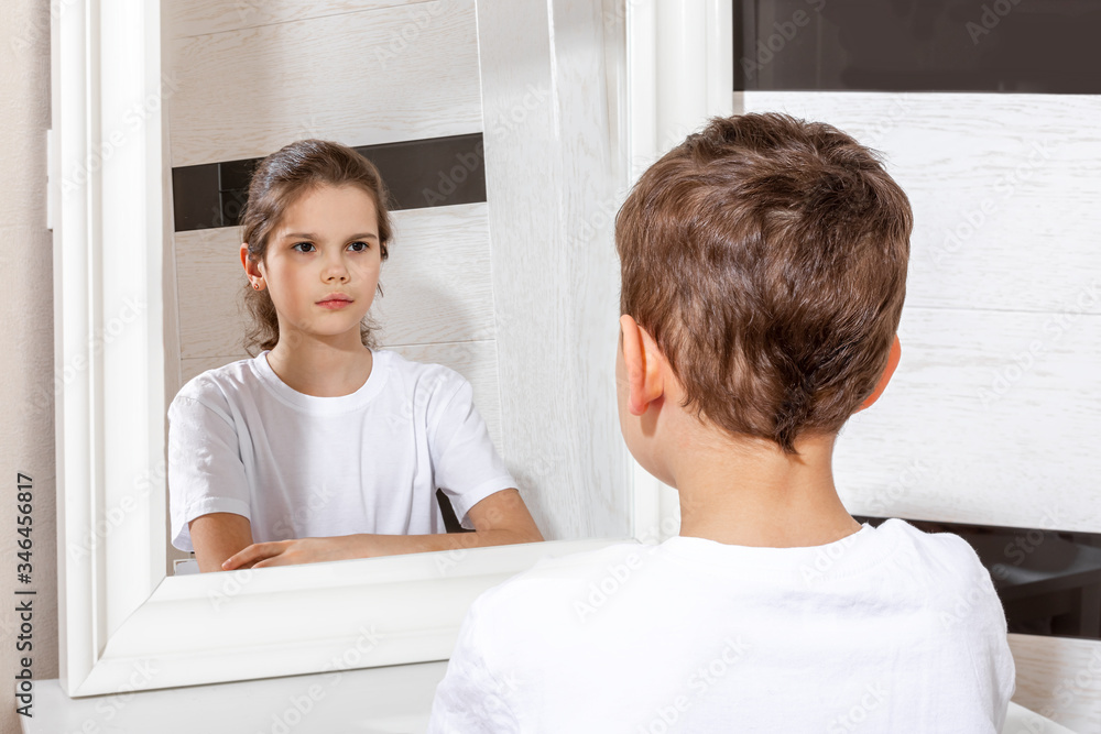 Reflection of a boy in the mirror by a girl. Sister and brother concept