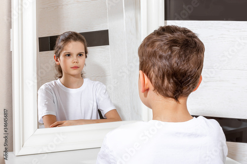 Reflection of a boy in the mirror by a girl. Sister and brother concept. Boy and girl. Concept of Gender dysphoria.
