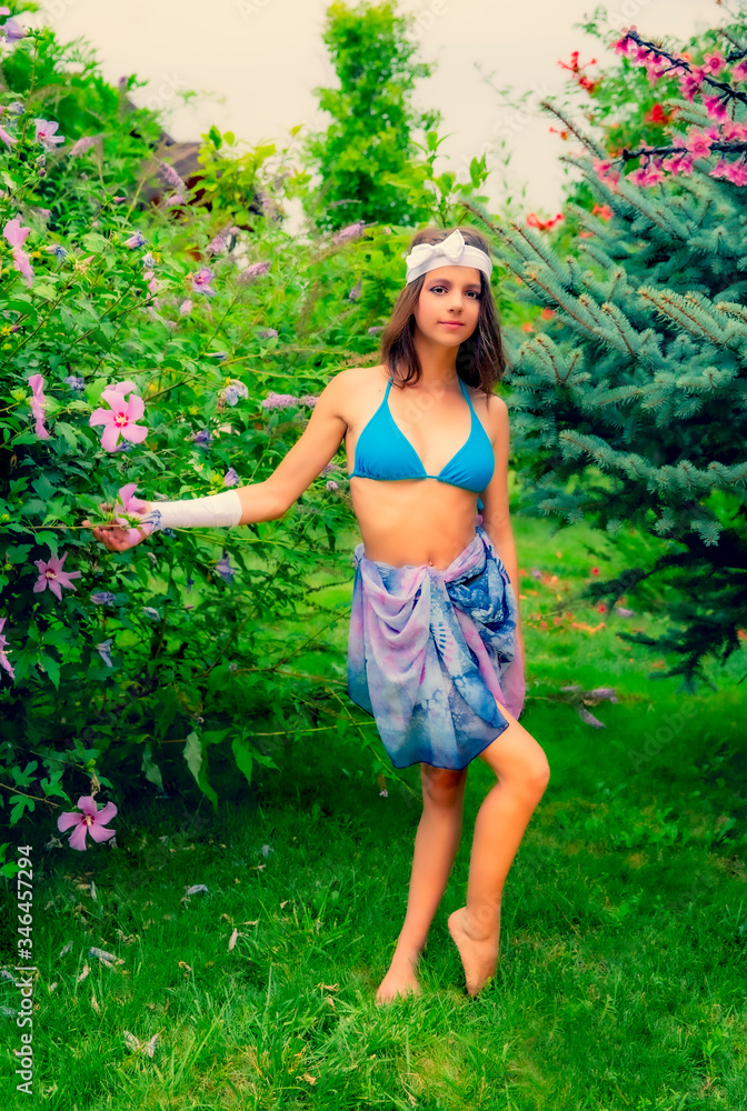 Model looking Girl standing in a swimsuit on the background of green grass and forest. Model looking Girl standing in a swimsuit on the background of green grass and forest.