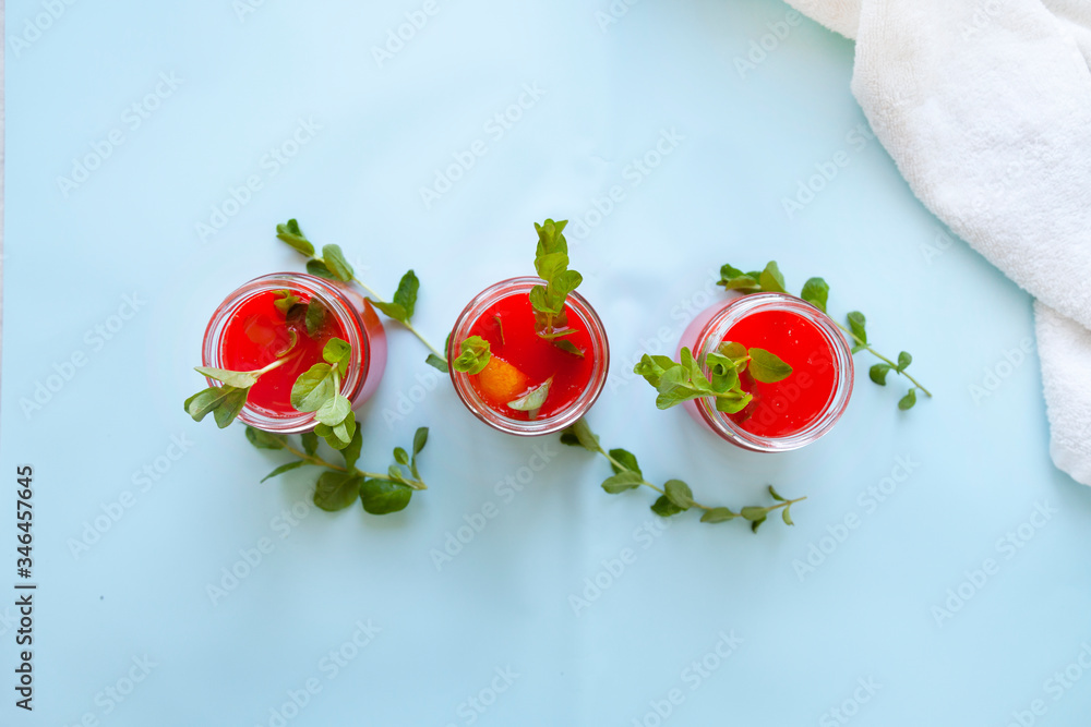 Glasses of homemade cold juice with mint with fresh berries on a light background. Selective focus. Glasses of homemade cold juice with mint with fresh berries on a light background. Selective focus.