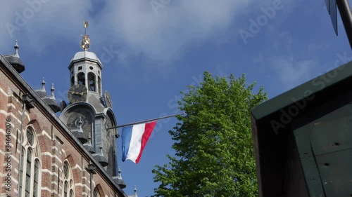 Slide shot of Dutch flag hanging at half mast on bell tower on a sunny day against a blue sky photo