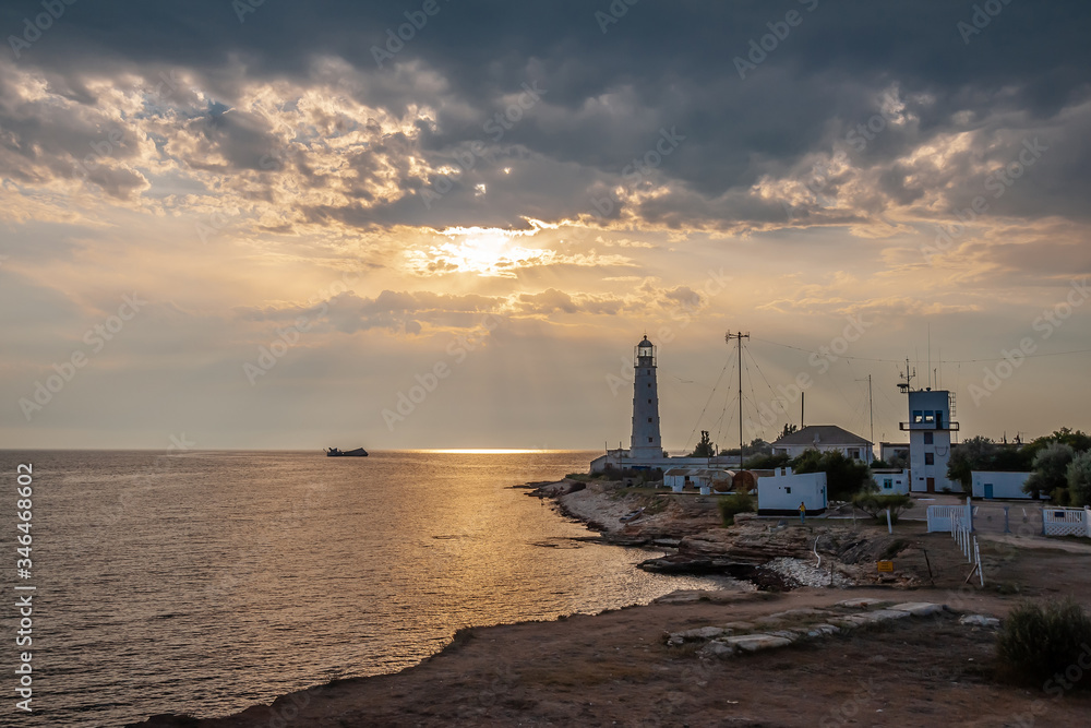 Lighthouse on the seashore at sunset