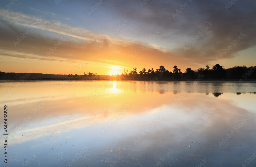 beautiful sunrise reflected in big forest lake