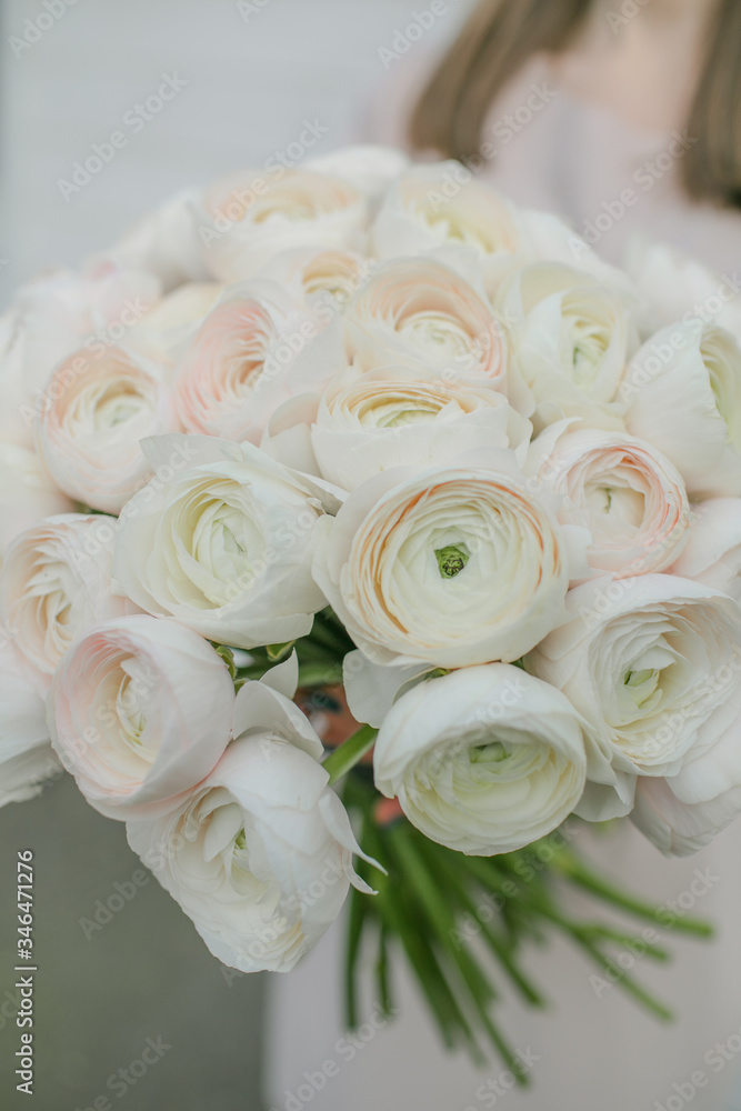 Obraz premium White peony roses bouquet in girl's hands by the Brick wall