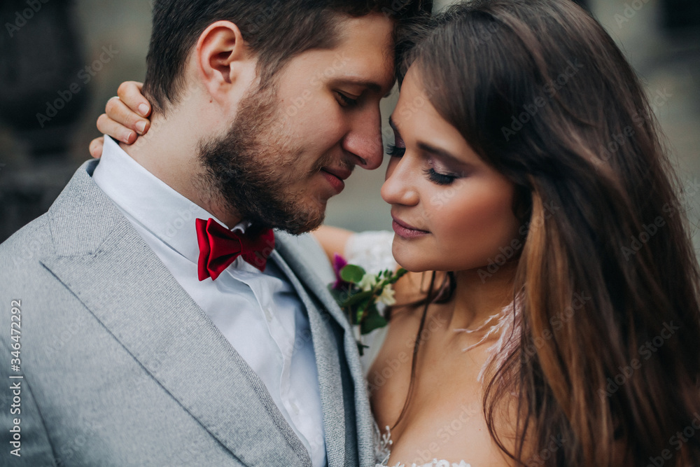 Beautiful bride and groom embracing and kissing on their wedding day outdoors Beautiful bride and groom embracing and kissing on their wedding day outdoors