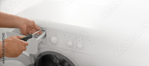 Obraz na plátně Professional plumber repairing broken washing machine, space for text