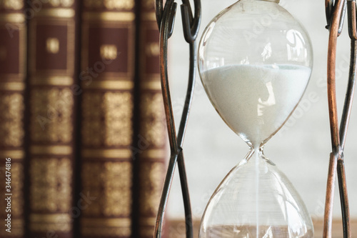Vintage hourglass against a stack of old books close up