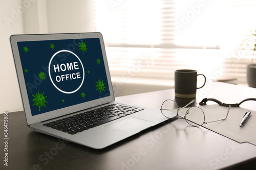 Modern laptop with text HOME OFFICE on table indoors