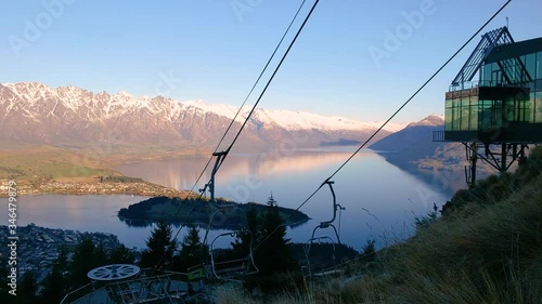 Scenic Sunset Timelapse Of Cableway Gondola With Panoramic Views Of The Reflective Lake And Snow Capped Mountains Of Queenstown, New Zealand.