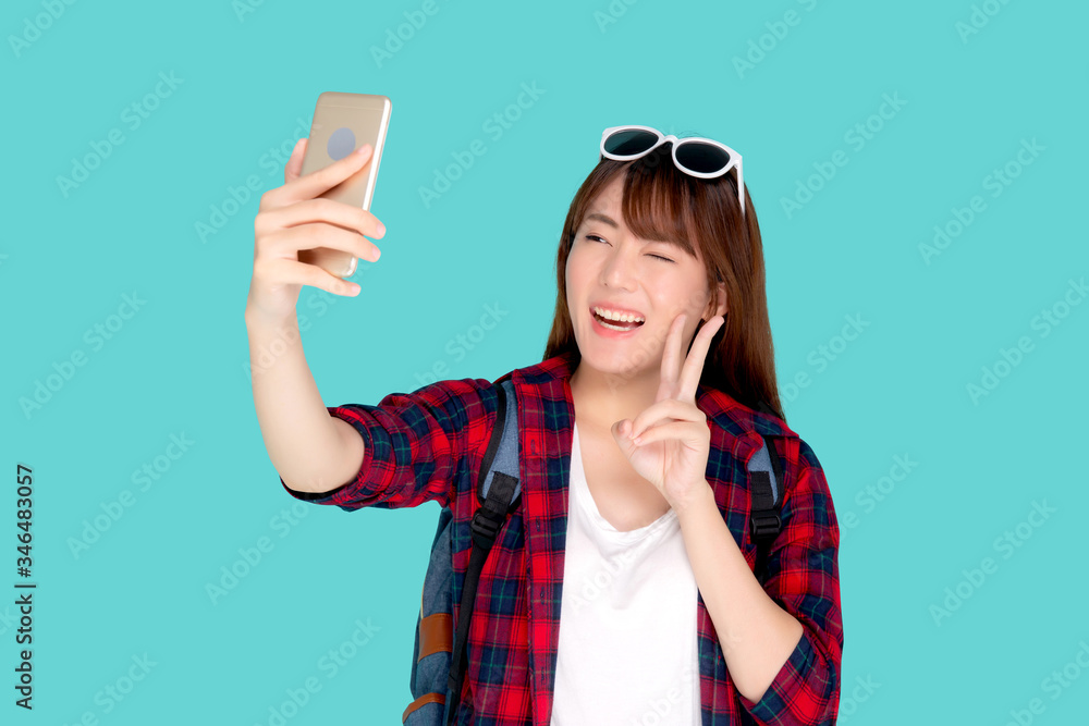 Beautiful portrait young asian woman cheerful smiling and take selfie on smart mobile phone, beauty girl wear travel summer enjoy and fun in vacation isolated on blue background, holiday concept.