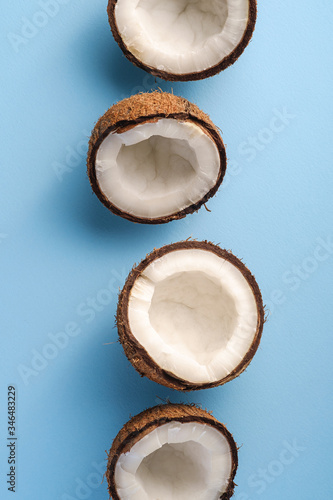 Coconut fruits in row on blue vibrant plain background, abstract food tropical concept, top view