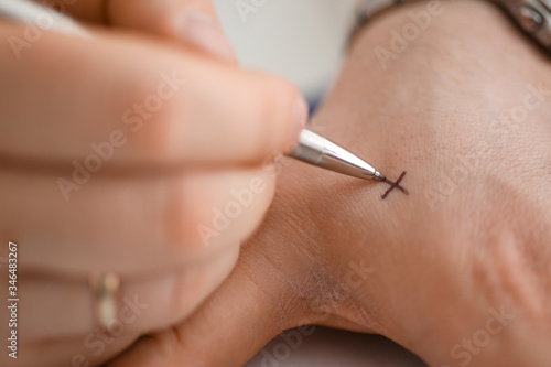 Male make x cross note with silver pen at his arm