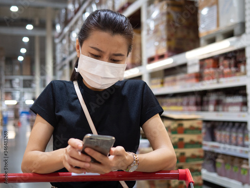Woman wearing disposable protective face mask shopping in supermarket during coronavirus pneumonia outbreak