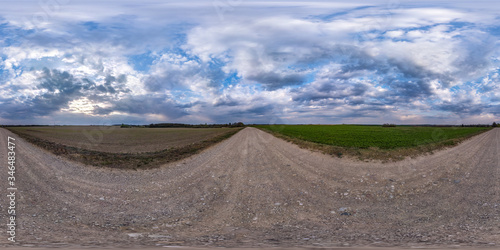 full seamless spherical hdri panorama 360 degrees angle view on gravel road among fields in spring day with storm clouds before rain in equirectangular projection, ready for VR AR content